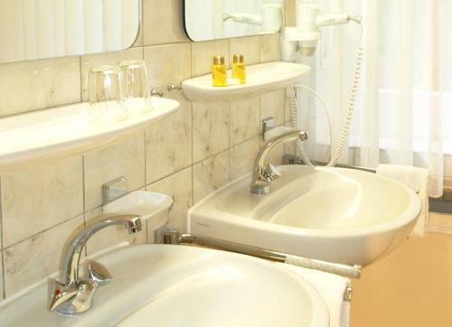 a white bathroom with a sink and a mirror at Heidehotel Waldhütte in Telgte