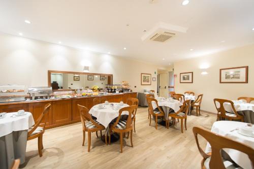 a restaurant with tables and chairs and a kitchen at Diana Park Hotel in Florence