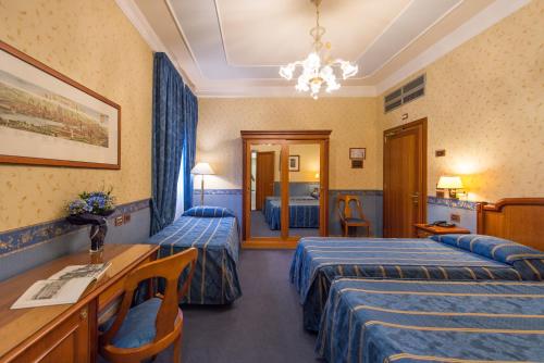 a hotel room with two beds and a desk at Diana Park Hotel in Florence