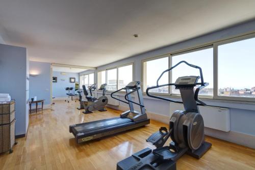 a gym with treadmills and ellipticals in a room with windows at Mercure Catania Excelsior in Catania