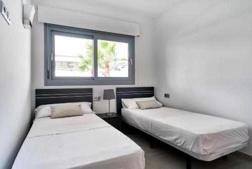 2 camas en una habitación con ventana en Orange Holiday Housing - Villa Amalia 13, en Torrevieja