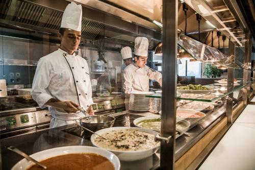 a group of chefs preparing food in a kitchen at Cosmo Hotel Palace in Cinisello Balsamo