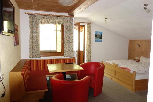 1 dormitorio con cama, escritorio y silla roja en Ferienhaus Inge, en Sankt Leonhard im Pitztal
