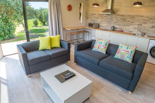 a living room with two couches and a table at Camp Waipu Cove in Waipu