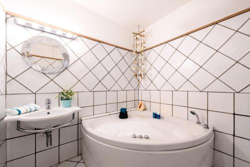 a white tiled bathroom with a tub and a sink at Cartiera Apartment with Pool by AMALFIVACATION in Amalfi