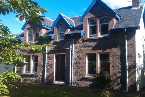 une maison en pierre avec un toit bleu dans l'établissement Seawinds, à Kyle of Lochalsh