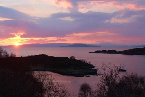 a sunset over a body of water with a boat at Seawinds in Kyle of Lochalsh