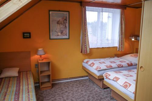 2 camas en una habitación con paredes de color naranja en Penzion Kapitan, en Jindřichův Hradec