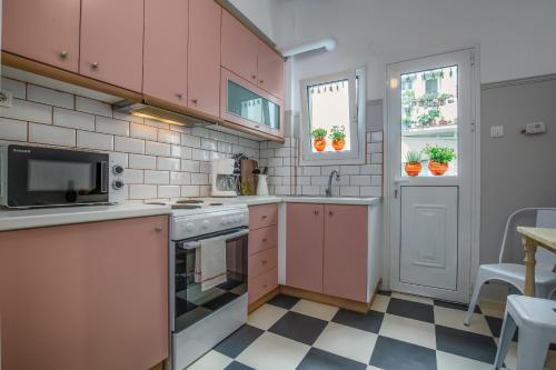 アテネにあるAbsolute Athens Iのピンクのキャビネットとチェッカー付きの床が備わるキッチン