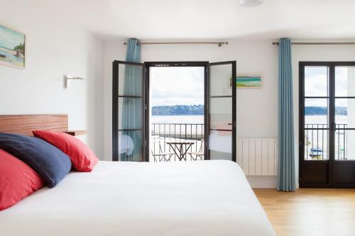 a bedroom with a white bed and a view of the water at Hotel du port in Locquirec