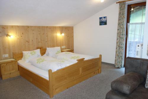 a bedroom with a wooden bed and a chair at Ferienhaus Inge in Sankt Leonhard im Pitztal