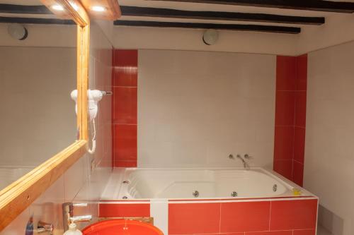 a bath tub in a bathroom with red and white walls at Hotel Spa Casa de Adobe Villa de Leyva in Villa de Leyva