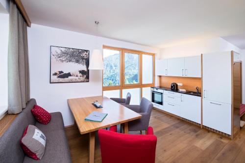 ein Wohnzimmer und eine Küche mit einem Tisch und einem Sofa in der Unterkunft Alpenrose Nassfeld in Sonnenalpe Nassfeld