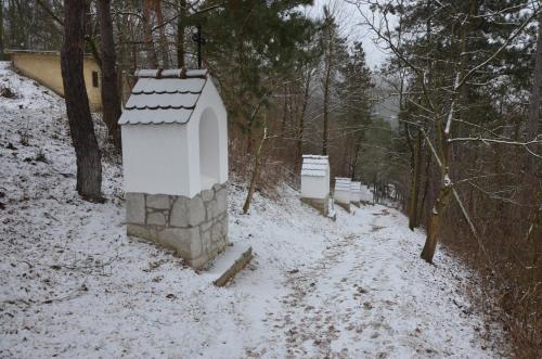 a snow covered path with benches in a forest at Őzgida Nyaralóház in Zebegény