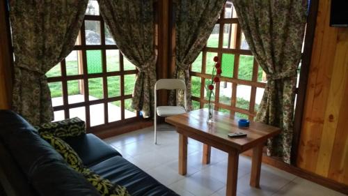 a living room with a couch and a table in front of a window at Cabañas Tornagaleones Villarrica in Villarrica