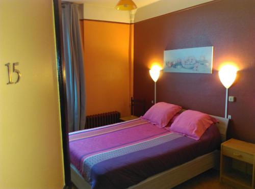 1 Schlafzimmer mit einem Bett mit rosa Kissen und 2 Lampen in der Unterkunft Hotel le Rallye in Soissons