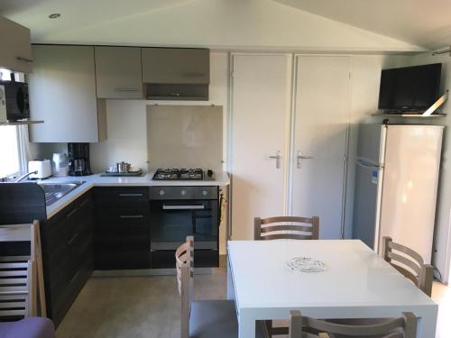 a kitchen with a white table and a white table and chairs at Fun Family Home - Camping Les Charmettes in Les Mathes