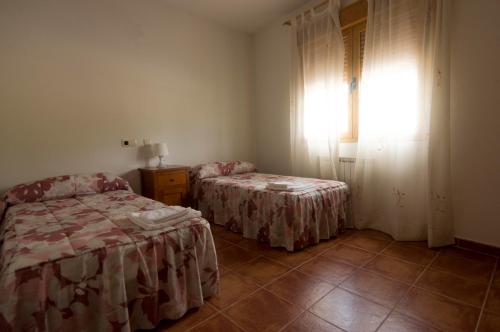 a bedroom with two beds and a window with curtains at Casa Mili in Azucaica