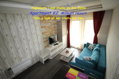 a living room with a blue couch and a tv at Apartment G10 Milmari resort in Kopaonik