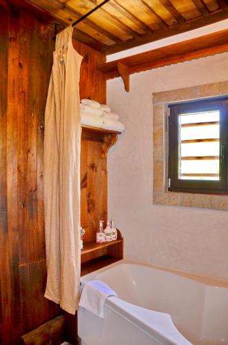 a bathroom with a tub and a wooden wall at Kalinia Guesthouse B&B in Kovačevica