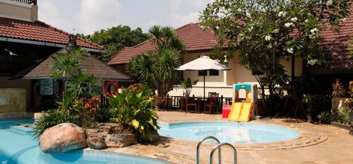 a swimming pool with a slide next to a house at Resor Tuban Tropis in Tuban