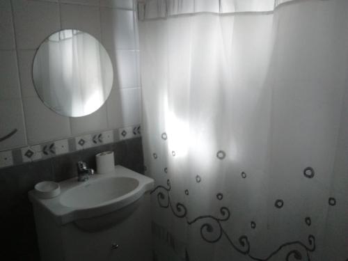 Baño blanco con lavabo y espejo en Casita Los Nogales en El Bolsón