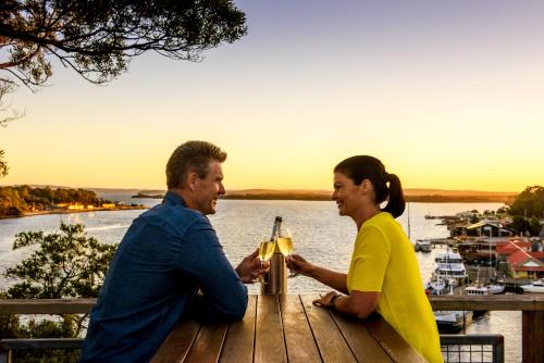 two people sitting at a picnic table with a beer at Strahan Village in Strahan