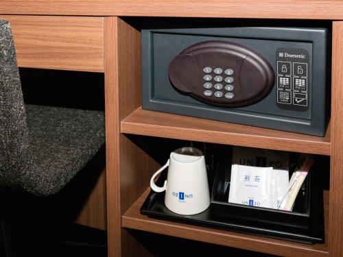 a microwave oven with a coffee mug in a cabinet at HOTEL UNIZO Osaka Umeda in Osaka