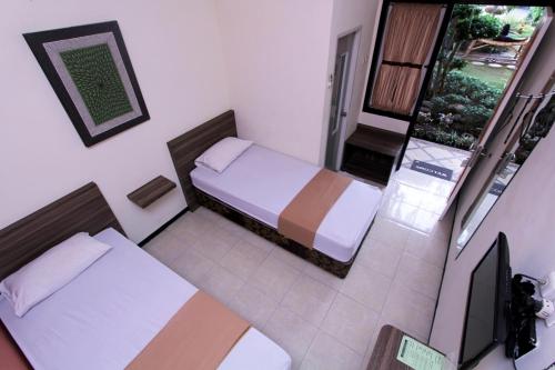 a small bedroom with two beds and a balcony at Guest House Rumah Wahidin Syariah in Probolinggo