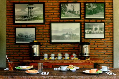 a table with plates of food and pictures on a brick wall at Guest House Rumah Wahidin Syariah in Probolinggo