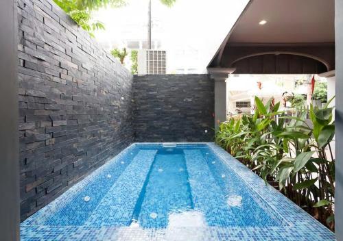 a swimming pool in a house with a brick wall at Sirinan Villa Nimman ChiangMai in Chiang Mai
