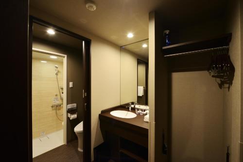 a bathroom with a sink and a toilet and a mirror at Hotel Kuu Kyoto in Kyoto