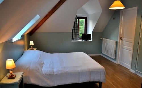 a bedroom with a large white bed and a window at Manoir de Kerangosquer in Pont-Aven