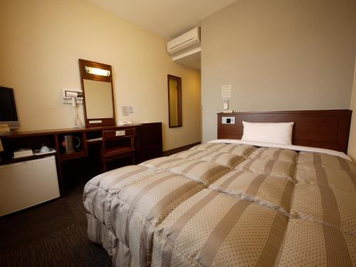 諫早市にあるホテルルートイン諫早インターの大きなベッドとバスルームが備わるホテルルームです。