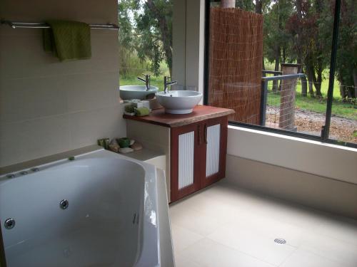 a bathroom with two sinks and a bath tub at Silversprings cottages in Metricup