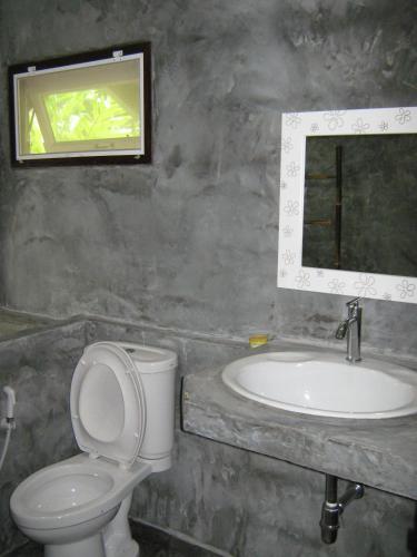a bathroom with a sink and a toilet and a mirror at BanJankapor in Kaeng Krachan