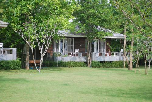 ein Haus mit Stühlen und einem Rasen davor in der Unterkunft BanJankapor in Kaeng Kachan