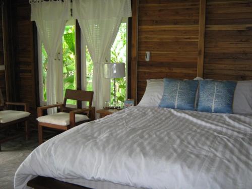ein Schlafzimmer mit einem Bett, einem Stuhl und einem Fenster in der Unterkunft BanJankapor in Kaeng Kachan