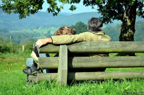 un hombre y una mujer sentados en un banco del parque en Au Beau Rivage, en Trois-Ponts