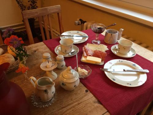 a table with a red table cloth with plates and cups at Pension Waldesblick in Friedrichroda