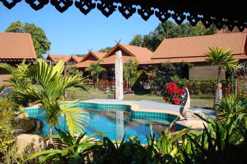 a swimming pool in front of a house with a fountain at Viang Yonok Hotel, Restaurant, Sports Club in Chiang Saen