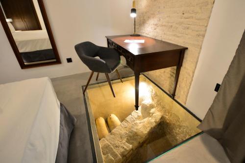 a glass floor with a desk and a chair in a room at Legado Alcazar Hotel in Seville