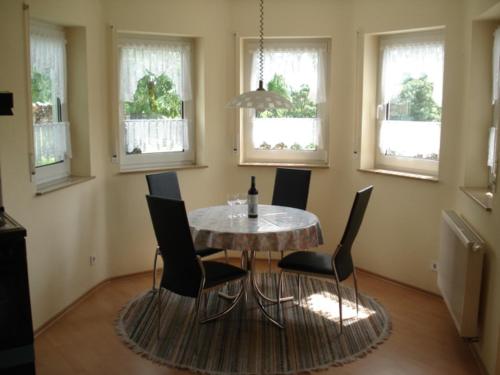 een eetkamer met een tafel, stoelen en ramen bij Gästehaus Kiefer in Klingenmünster