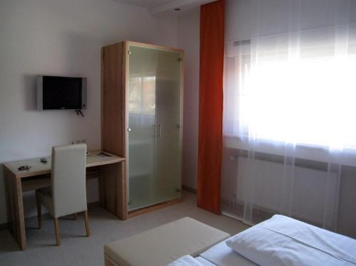Schlafzimmer mit einem Bett, einem Schreibtisch und einem TV in der Unterkunft Hotel Barbarina in Tübingen