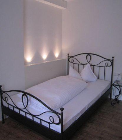 a bed in a room with lights on the wall at Hotel Barbarina in Tübingen