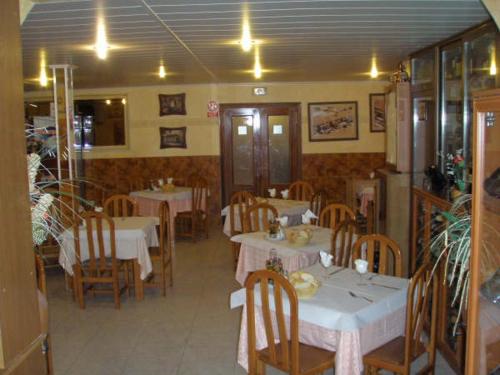 un restaurante con mesas blancas, sillas de madera y registrador en Hostal Mays, en Numancia de la Sagra