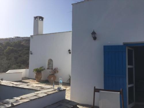 a white building with a blue door on the side of it at Aiolos in Skala