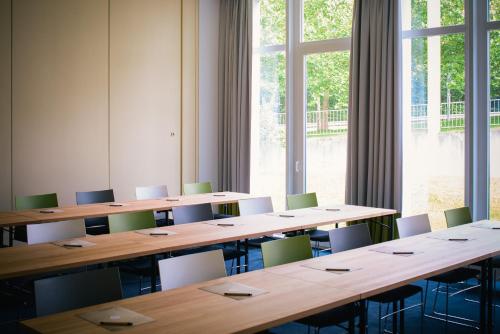 a room with tables and chairs and a large window at Vienna House Easy by Wyndham Trier in Trier