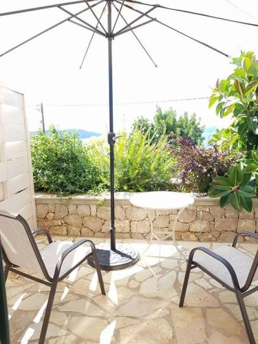 a patio with a table and chairs and an umbrella at Hotel Philip in Pylos
