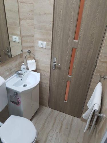 a bathroom with a toilet and a sink and a door at Onalisa in Arad